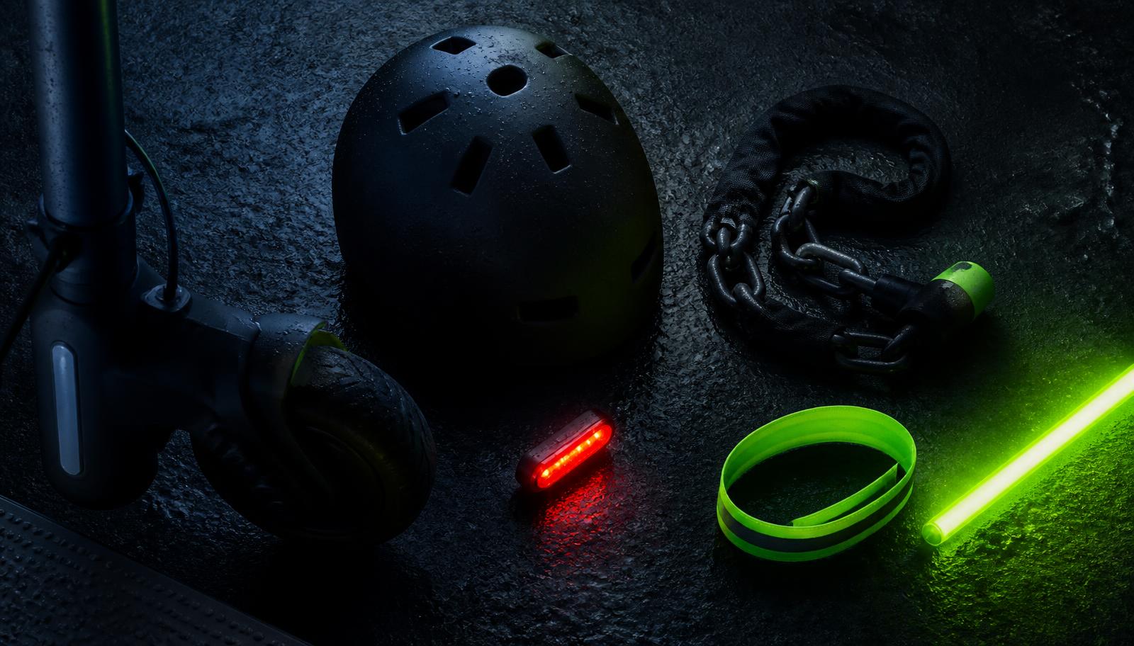 Casco, candado de cadena, luz trasera y banda reflectante sobre asfalto oscuro